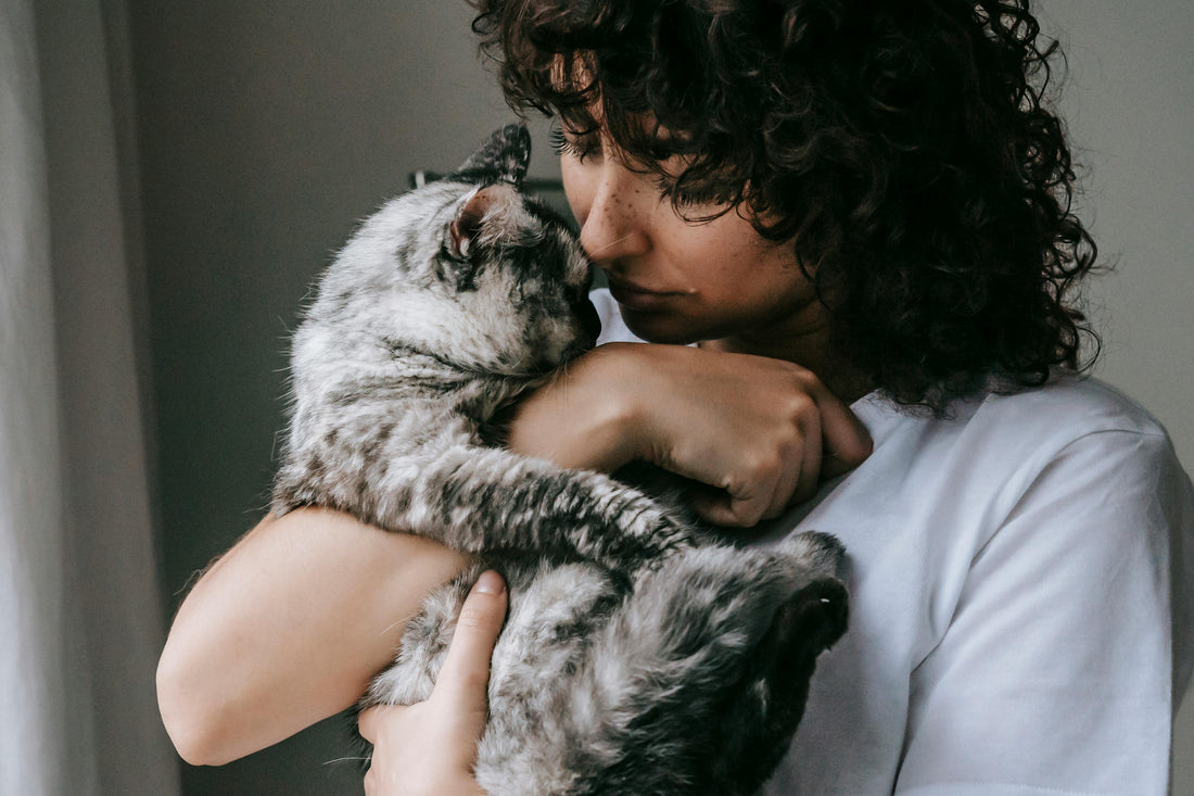 Eine dunkelhaarige Frau kuschelt mit ihrer Katze